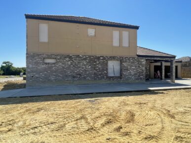 A house is being built in front of a dirt road.