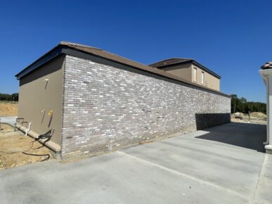 A house with a brick wall and a driveway.