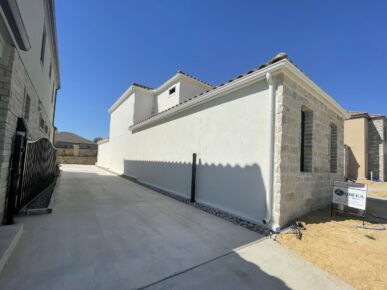 A driveway leading to a house with a white fence.