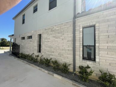 The front of a house with a stone wall.