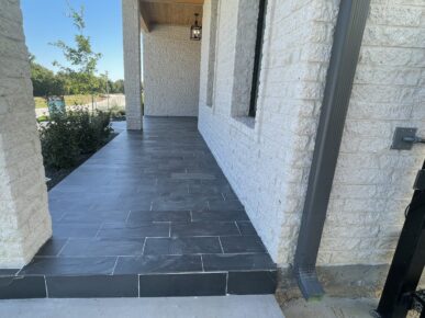 A walkway with black tile and a brick wall.