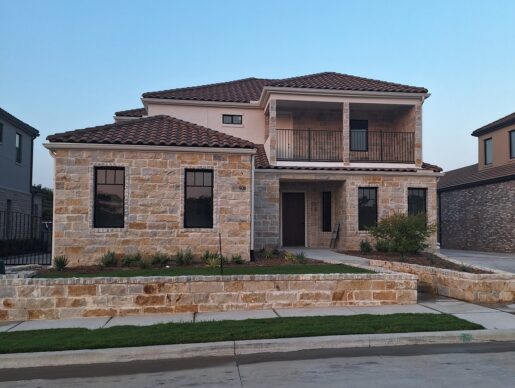 A home with a stone front and a brick driveway.