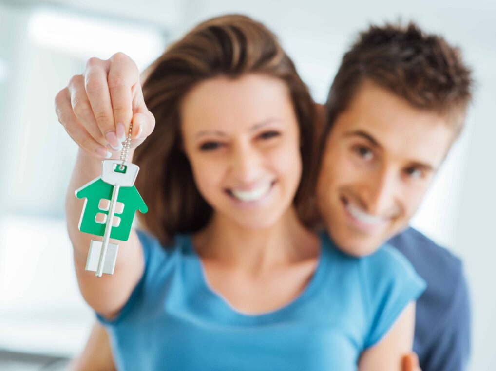 A man and woman holding up a house key. A man and woman holding up a house key.