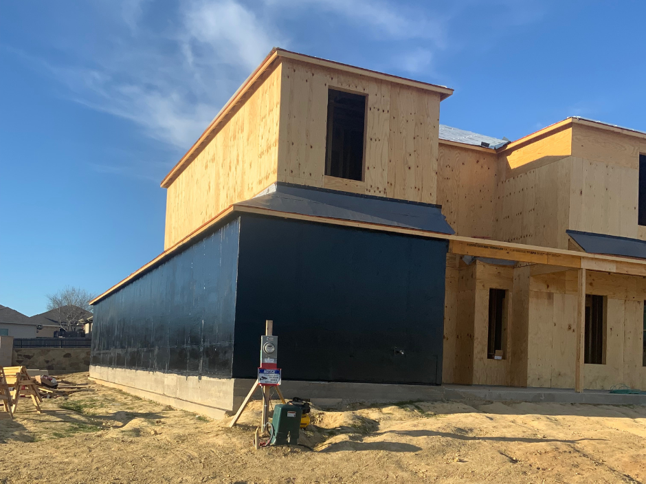A house under construction with black siding.