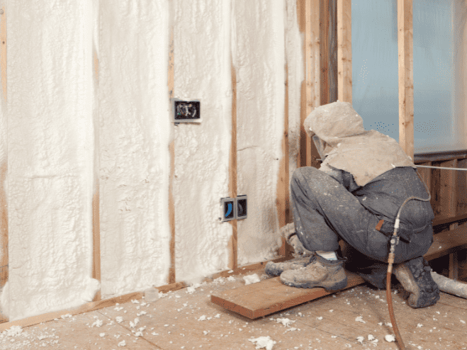 A man is working on a wall with insulation. A man is working on a wall with insulation.