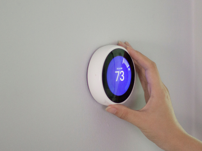 A person holding a nest smart thermosta.