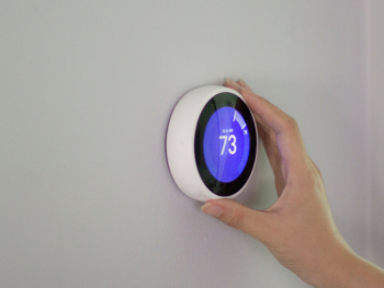 A person holding a nest smart thermosta.